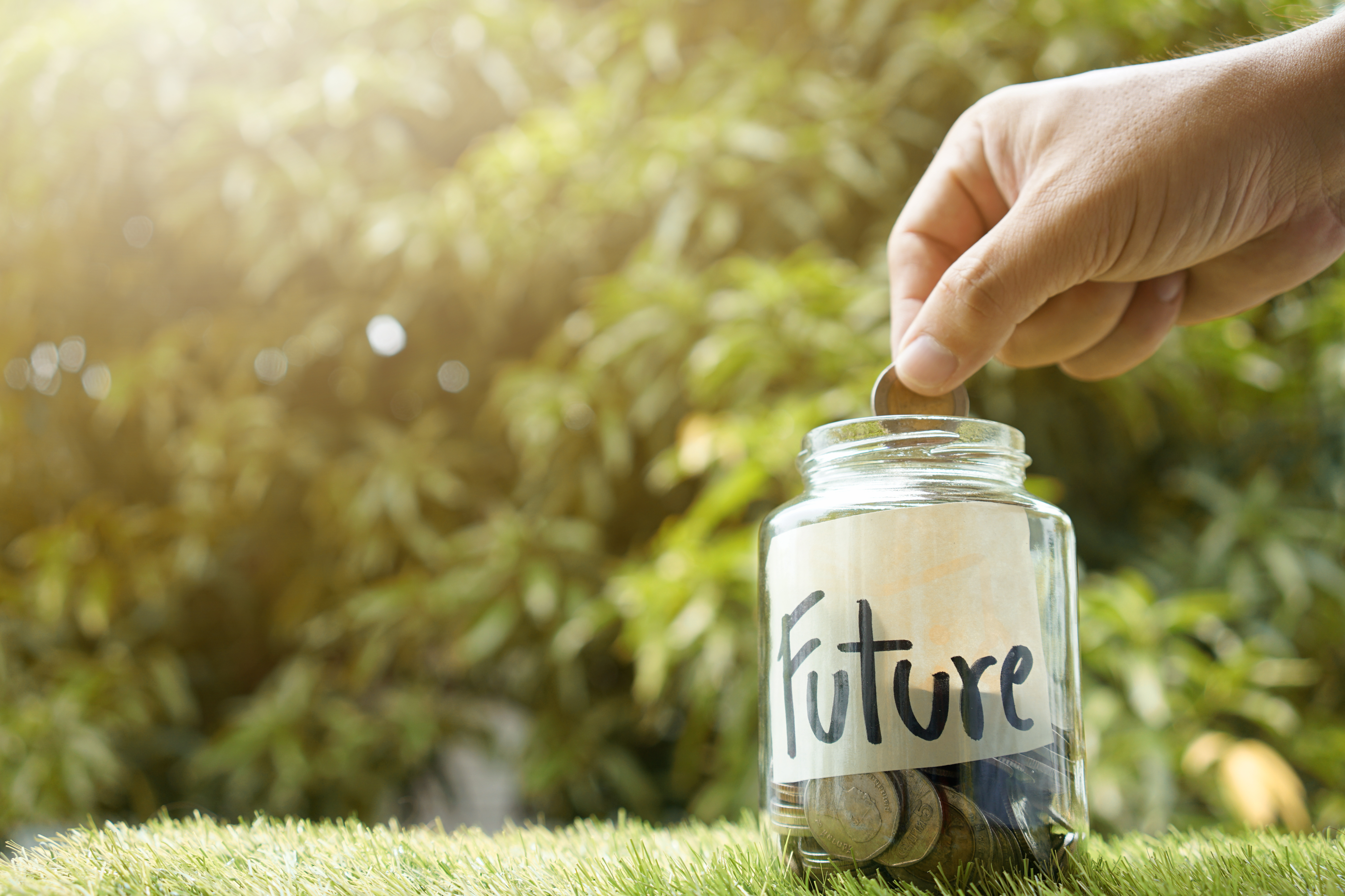 hand dropping change into glass jar labeled "future"