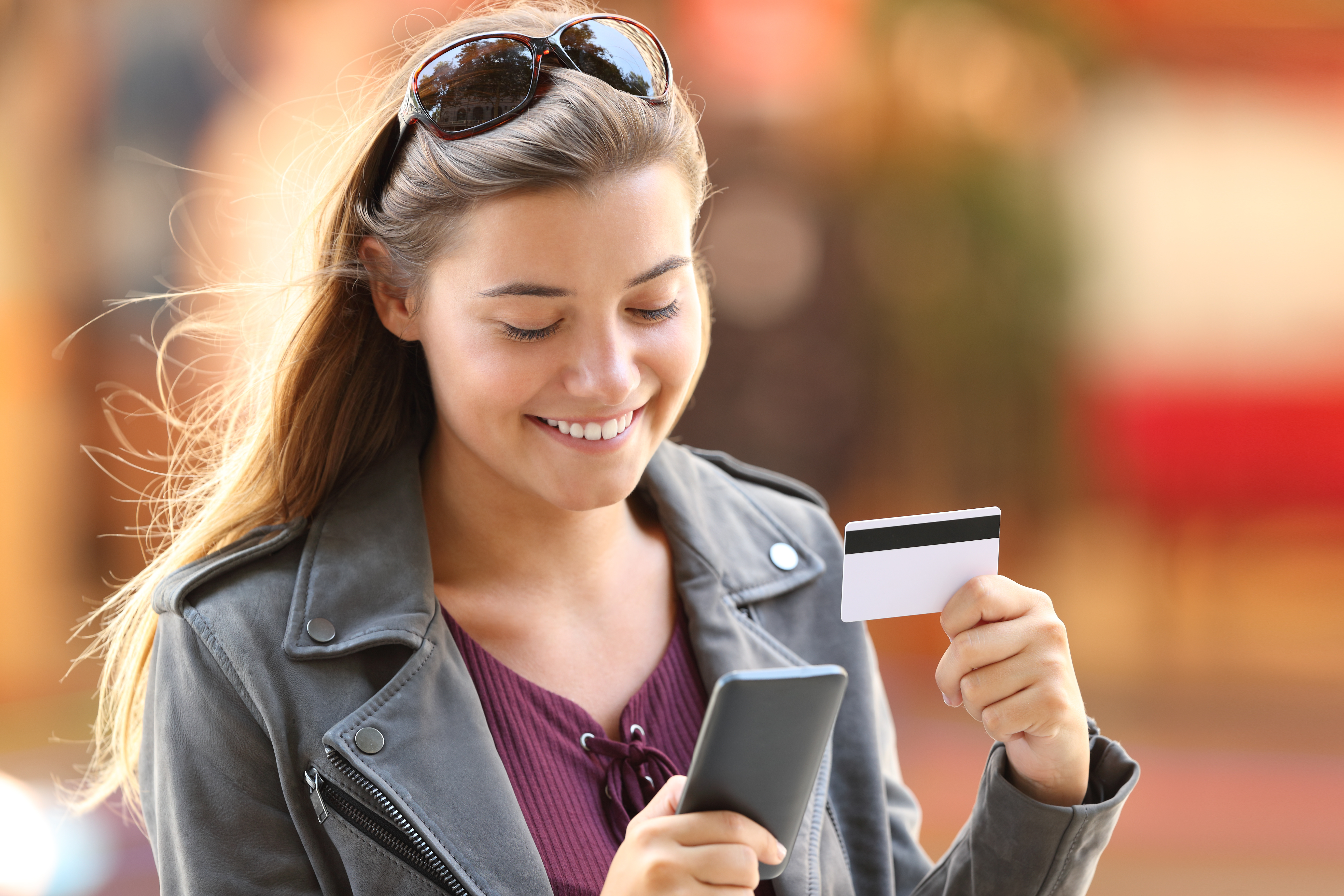 teen girl smiling at phone holding debit card